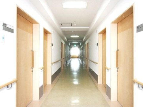 廊下には、全ての壁に手すりを取り付けている。両側に並ぶ居室ドアは引き戸になっている。突き当りの窓から光が差し込む明るい空間である。