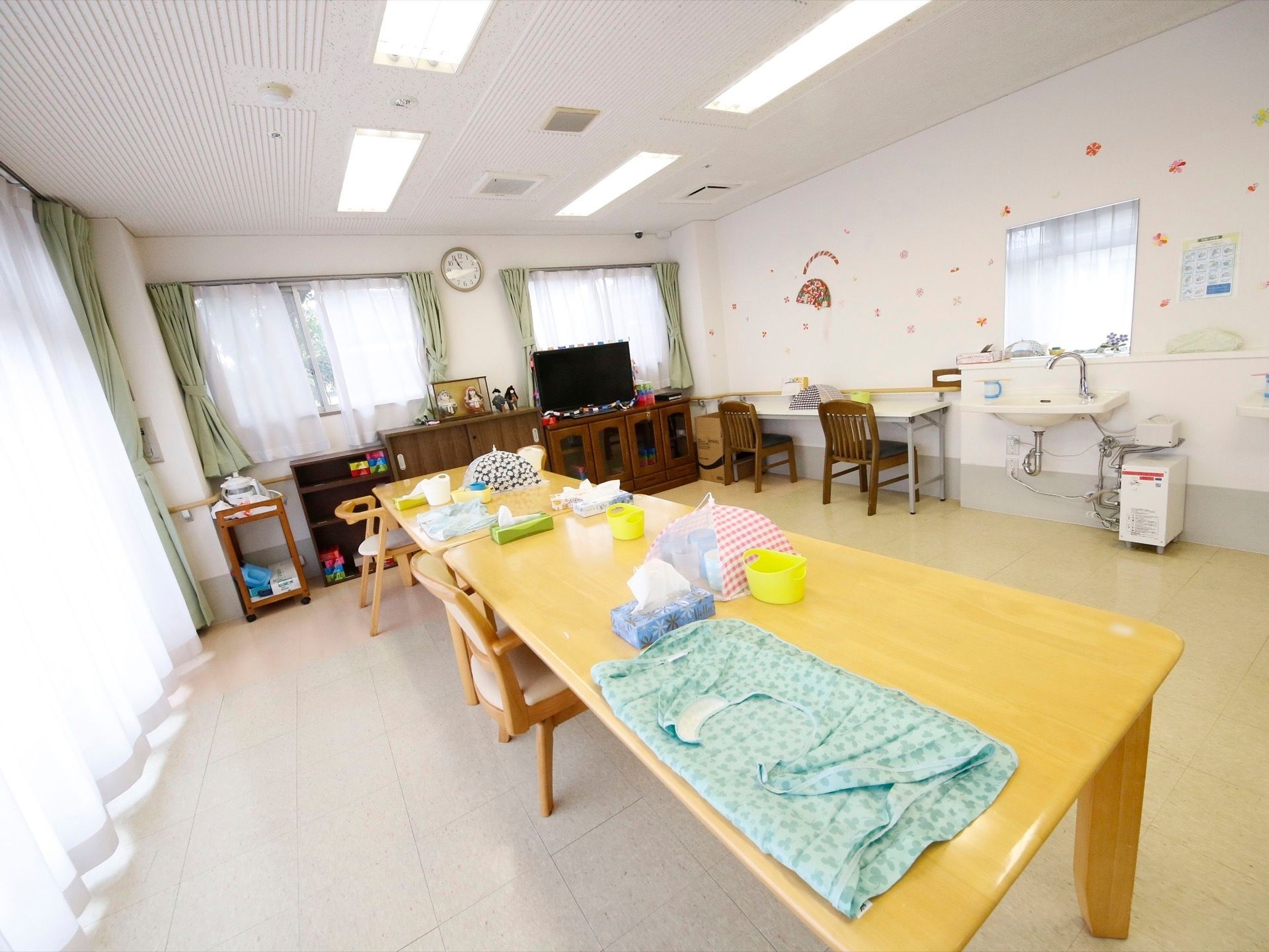 通路が広めで車椅子が通りやすくなっている。壁際には人形が飾ってある。二面が窓となっていて日光が良く入る部屋になっている。