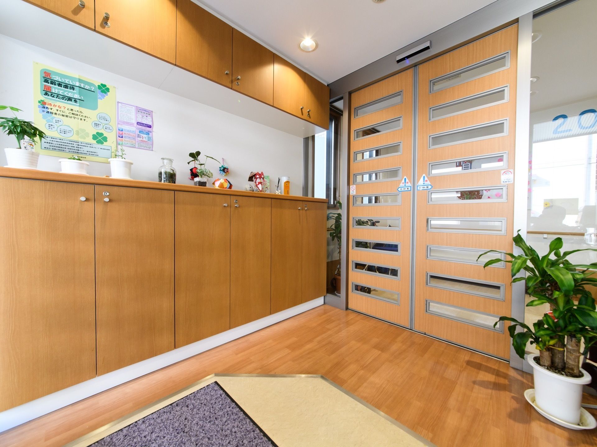 施設への入口は自動ドアになっている。靴箱が置かれているので、靴を脱いで施設に入る。バリアフリーの床になっている。