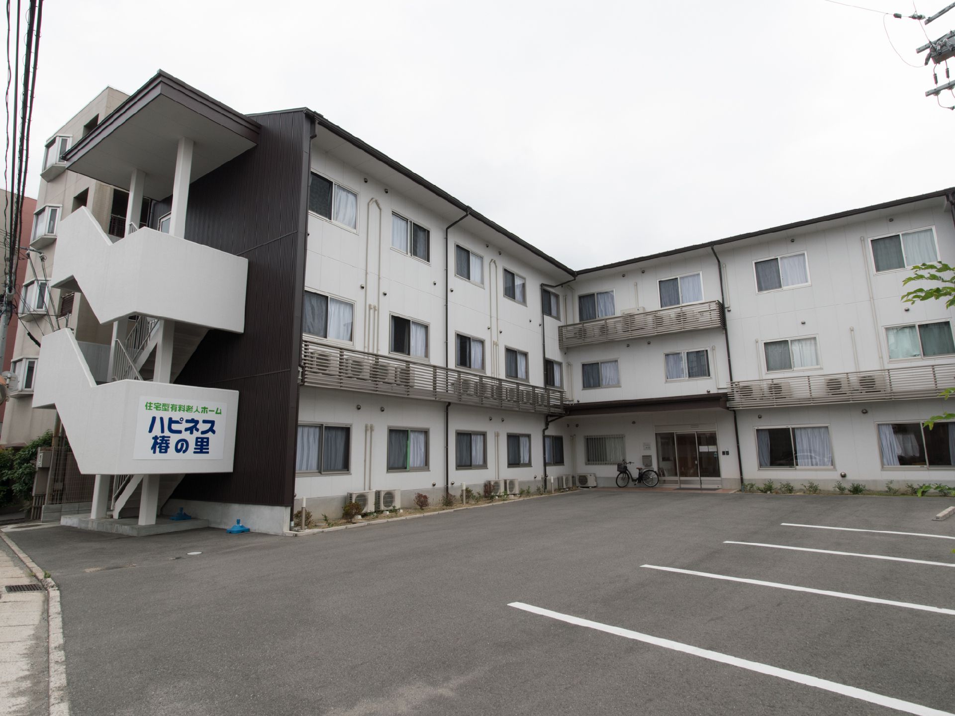 施設の建物構造は、鉄骨造3階建である。外階段の壁に施設名を表示している。壁が白いため、その文字は目立つ。