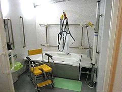 手すりや入浴補助器具が設置された浴室である。滑り止めマットが敷かれ安全性のある浴室で、入居者様の安心につながる。