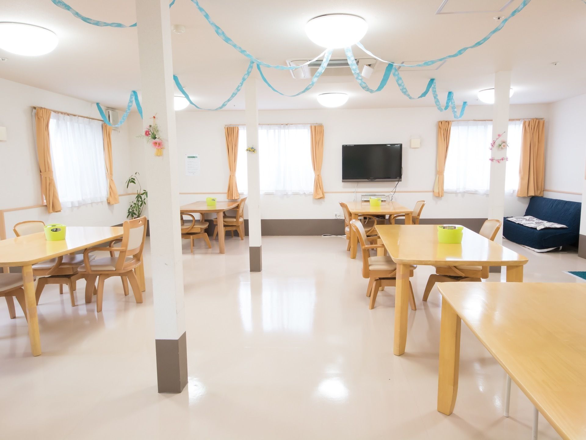 側面には、間隔を置いて窓が並んでいる。４人掛けのテーブルセットを配備し、正面にテレビを備え、横側の壁際にソファを置いている。