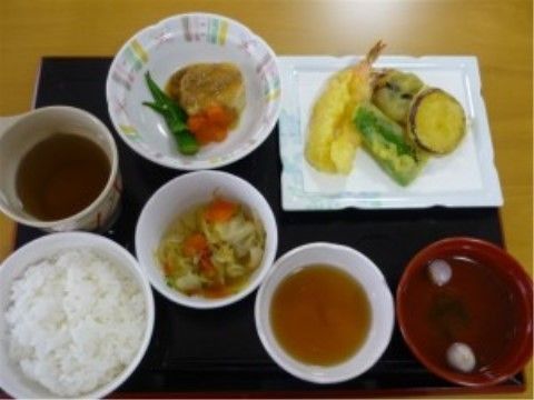 ある日の食事メニューである。黒いプレートに一汁三菜の献立で栄養バランスが考慮されている。色彩豊かに盛り付けされ配置されている。