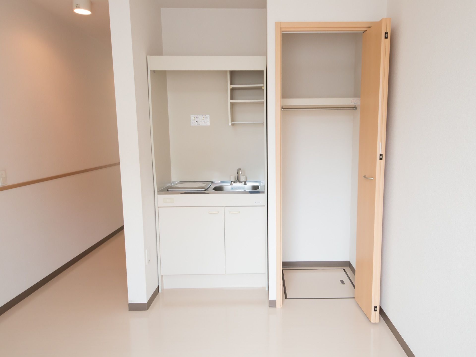 居室にはコンパクトなサイズのキッチンがあり、コンロはIH式となっている。キッチン台の上下には、キッチン用具を収納する棚が備わっている。