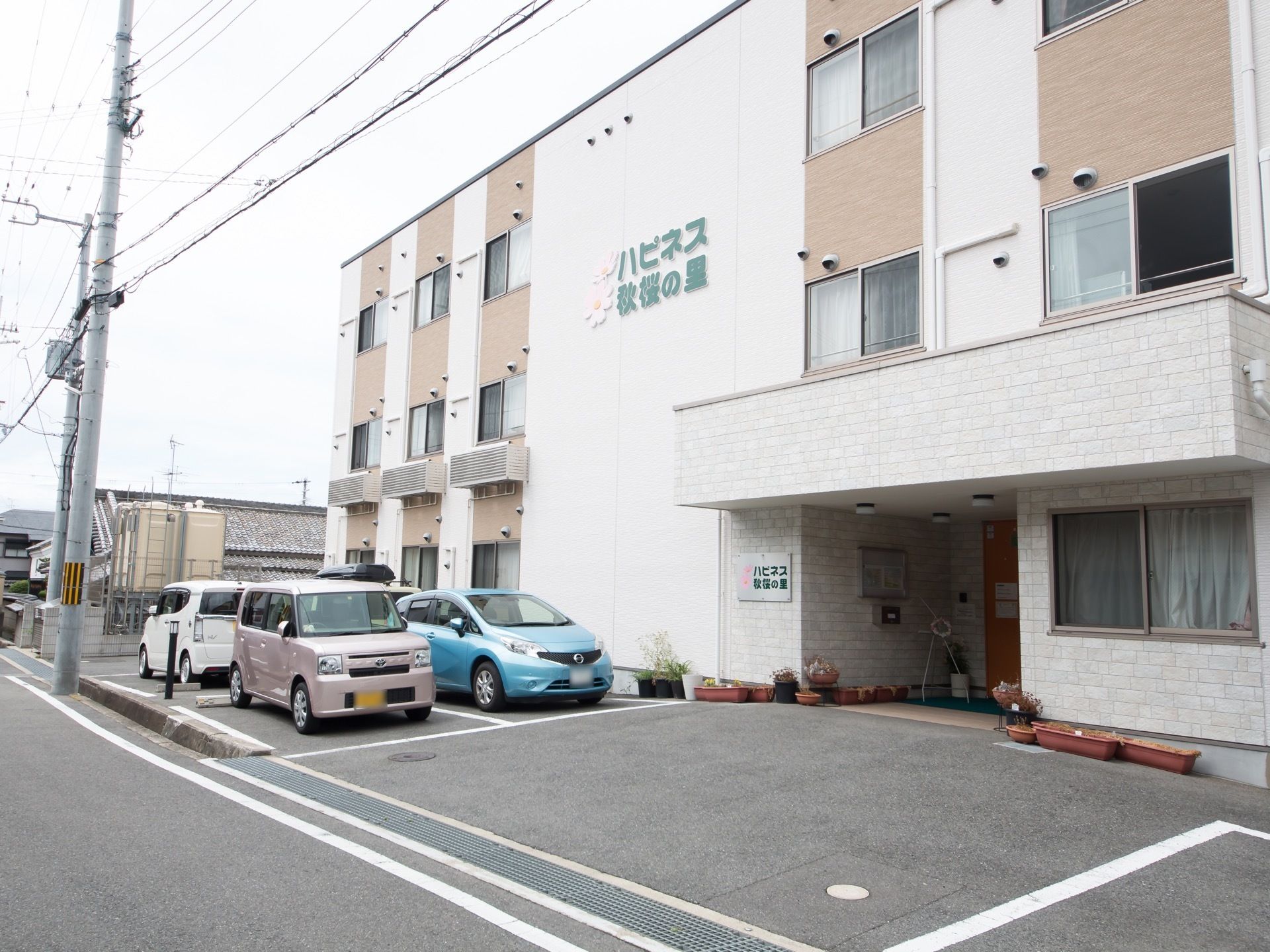 施設は明るい白と茶色の壁が交互に配置された、３階建てのコンパクトな建物である。建物前方の壁や入口手前には、施設名称が大きく表示されている。
