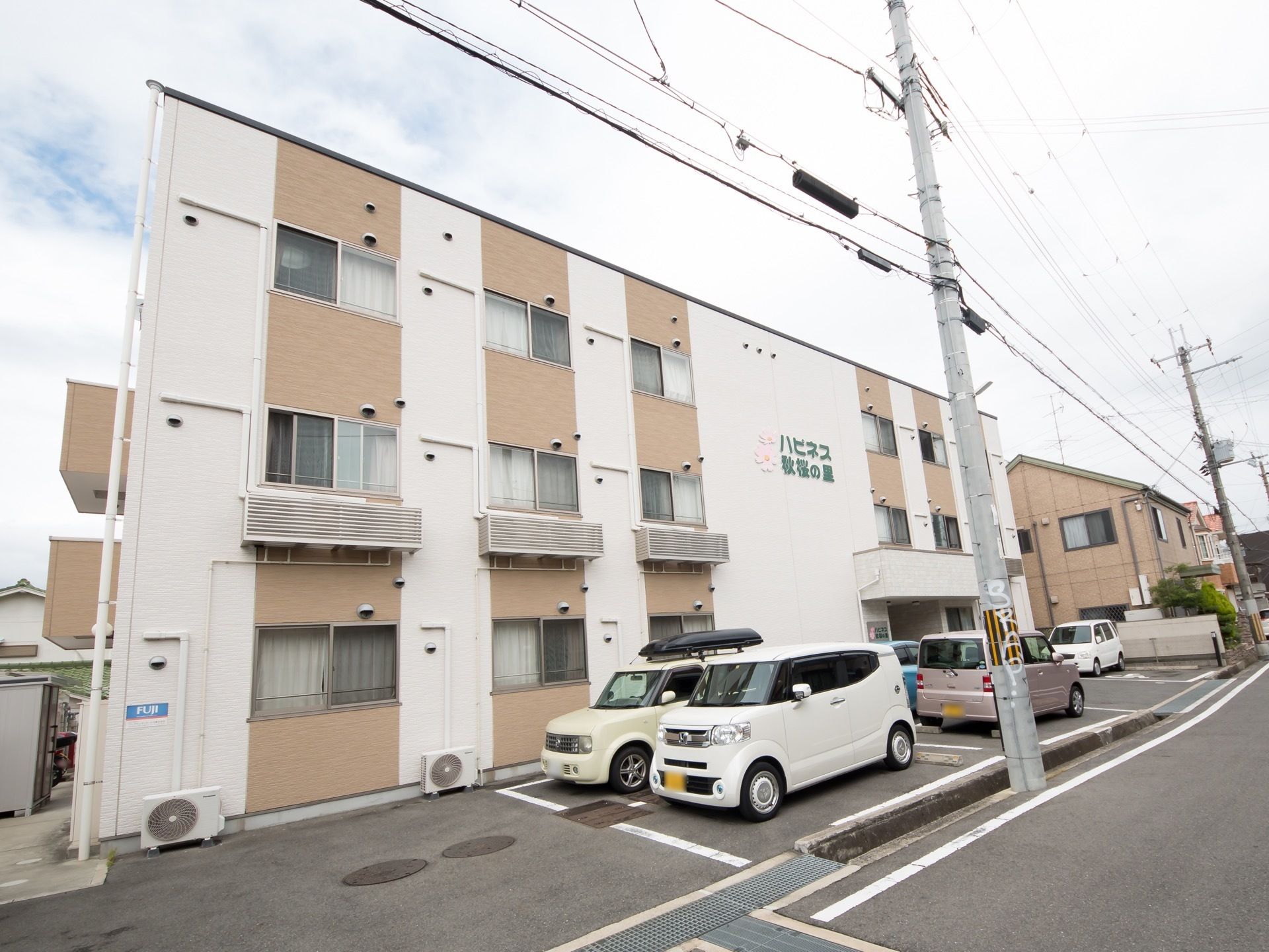 施設の前方には駐車用のスペースが確保されている。建物には窓が規則的に配置されており、自然光を施設全体に取り入れている。