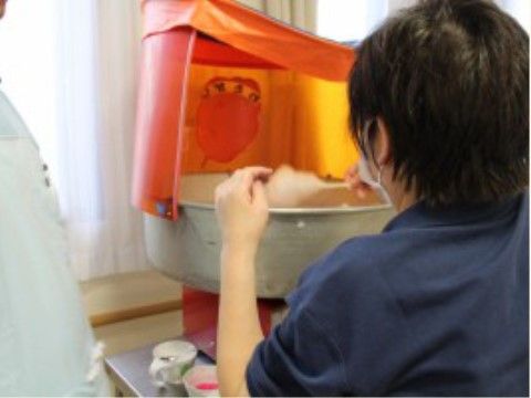 機械で綿飴を作るため、割り箸を回しながら糸を絡めていく施設職員