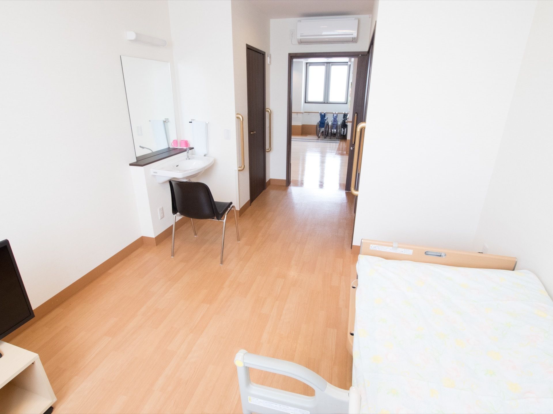 明るみのあるフローリング床を使用した、シンプルな居室である。大きな鏡が備えつけられた、白色の洗面台が完備されている。