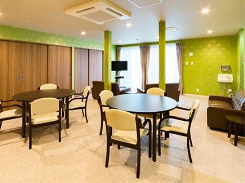 若葉色の鮮やかな壁紙におしゃれな家具が配置された談話スペースでは、テレビ鑑賞やティータイムをお楽しみいただける。