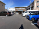 明るい日差しの施設外観と駐車場