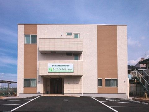 広々とした駐車場と屋根付きのポーチがある、四角い形の建物