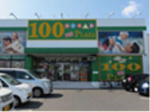 店舗の出入口上部と、右の壁面に緑色ベースに黄色で100円と書かれた大きな看板がある。他の壁面には親子の絵が描かれた楽しい感じの外観である。