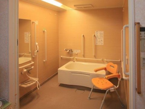 広めに設計された浴室である。空間内は電球色の照明で落ち着いた空間となっている。天井には換気扇が設置されている。