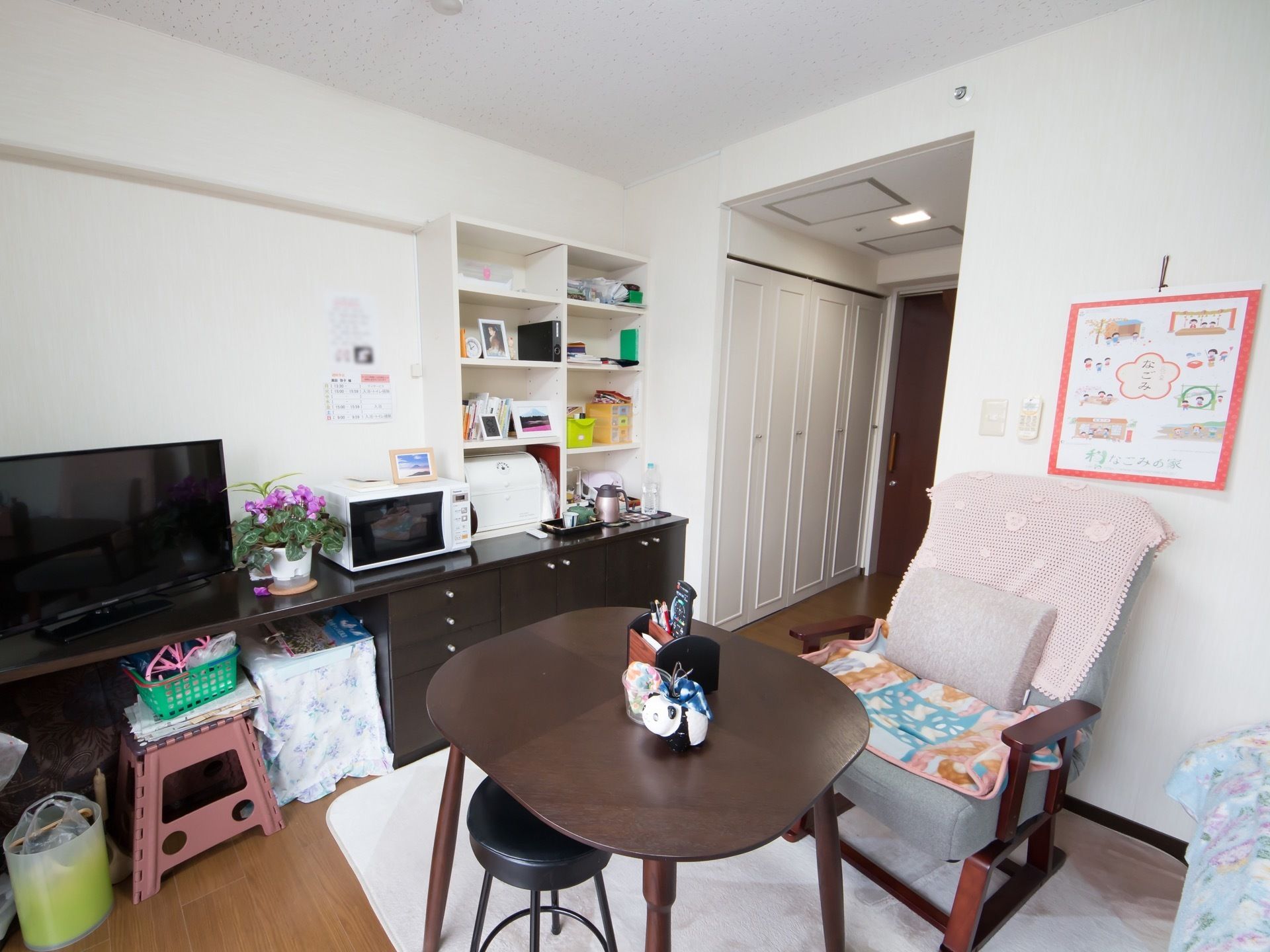 居室内には大型のクローゼットのほか、棚やテーブル、鉢植えなどが置かれている。テレビや電子レンジの家電もある。