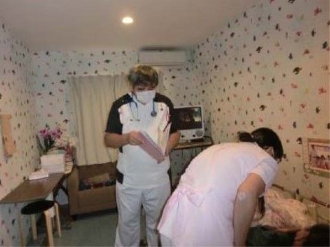 横になられているご入居様に声をかけているスタッフと医師