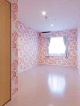 大きな花柄がデザインされた壁紙の居室である。天井には小型のダウンライトが設置されており、シンプルな空間になっている。
