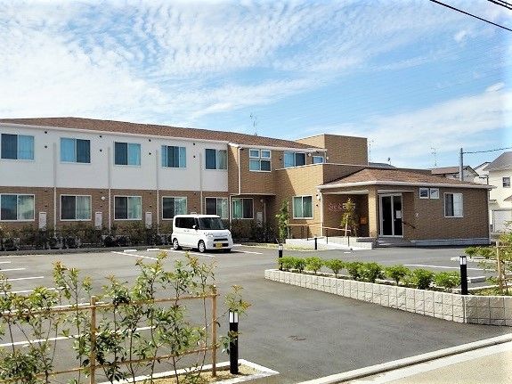 2階建ての建物は白とベージュで玄関先には手すり付きのスロープが付いている。