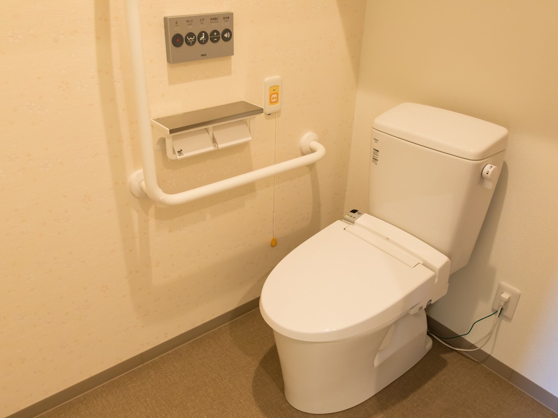 やわらかな照明の光で、落ち着いた雰囲気のトイレ。手すりが備え付けてあり、立ち座りの動作が無理なく行えるようになっている。