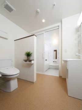 トイレの前に洗面台、奥には浴室がある。白を基調とした室内は清潔感に満ちている。小さいサイズの植木鉢も置かれている。