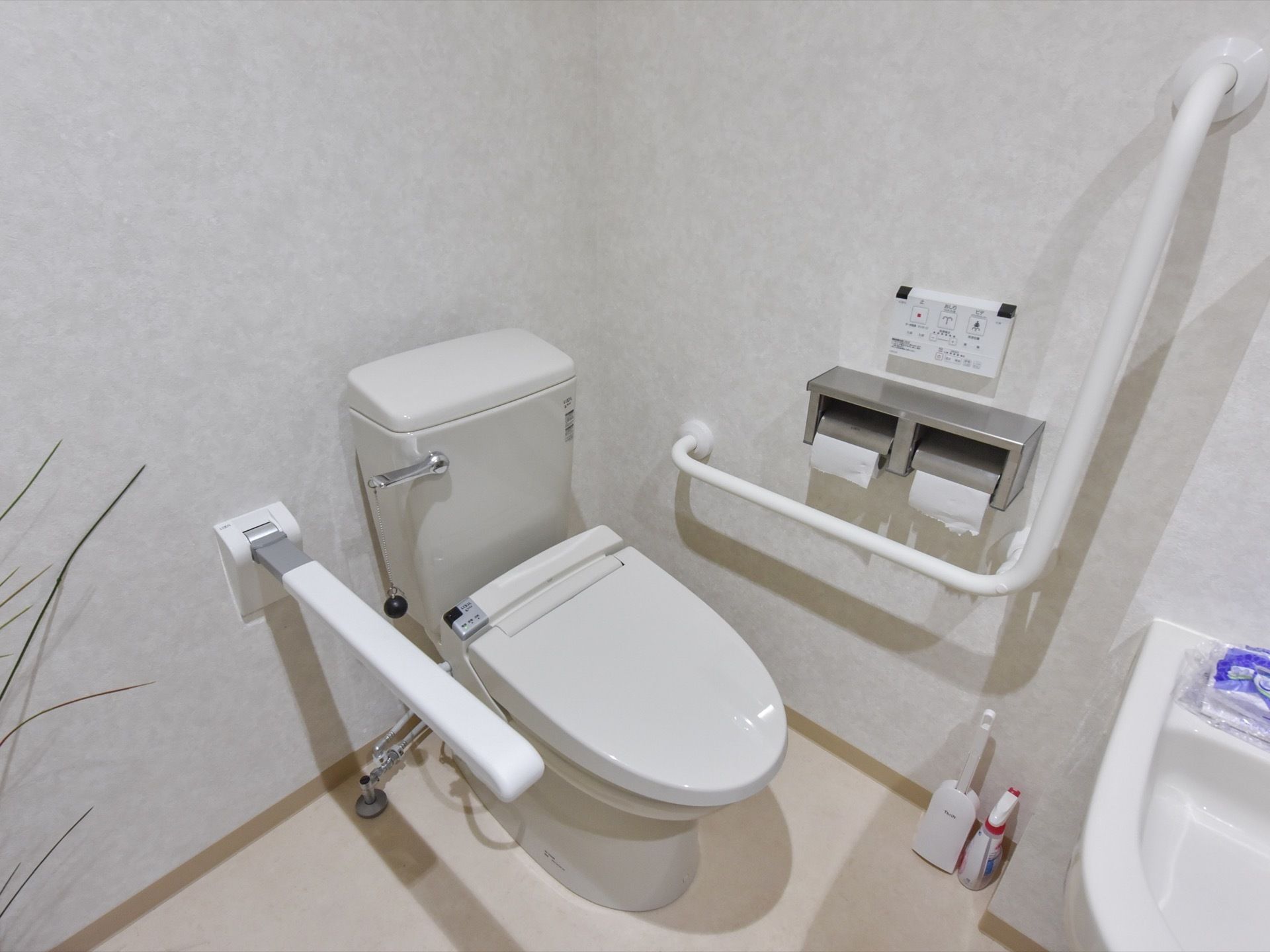 温水洗浄便座、手すりが完備されている。壁の手すりの他に可動式のものも設置されている。流水レバーは鎖をつけて、使いやすくしている。