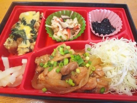 焼き肉をメインとしたお弁当。赤い容器におかずが乗せられている。