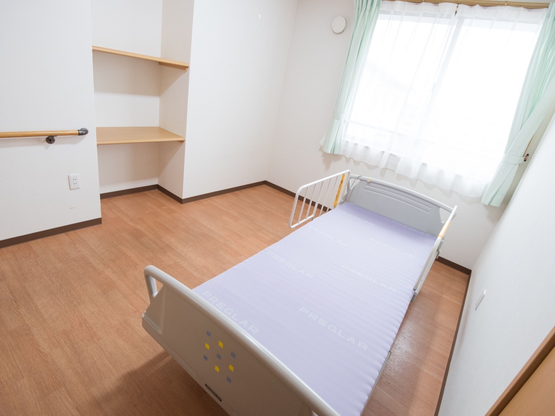 居室はフローリングの床で、壁には手すりが取りつけられている。ベッドは備えつけになっている。小窓が取りつけられている。