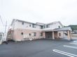 施設は白とベージュの２色使いである。敷地内に駐車スペースがあり、複数台の車を停めておくことができる。