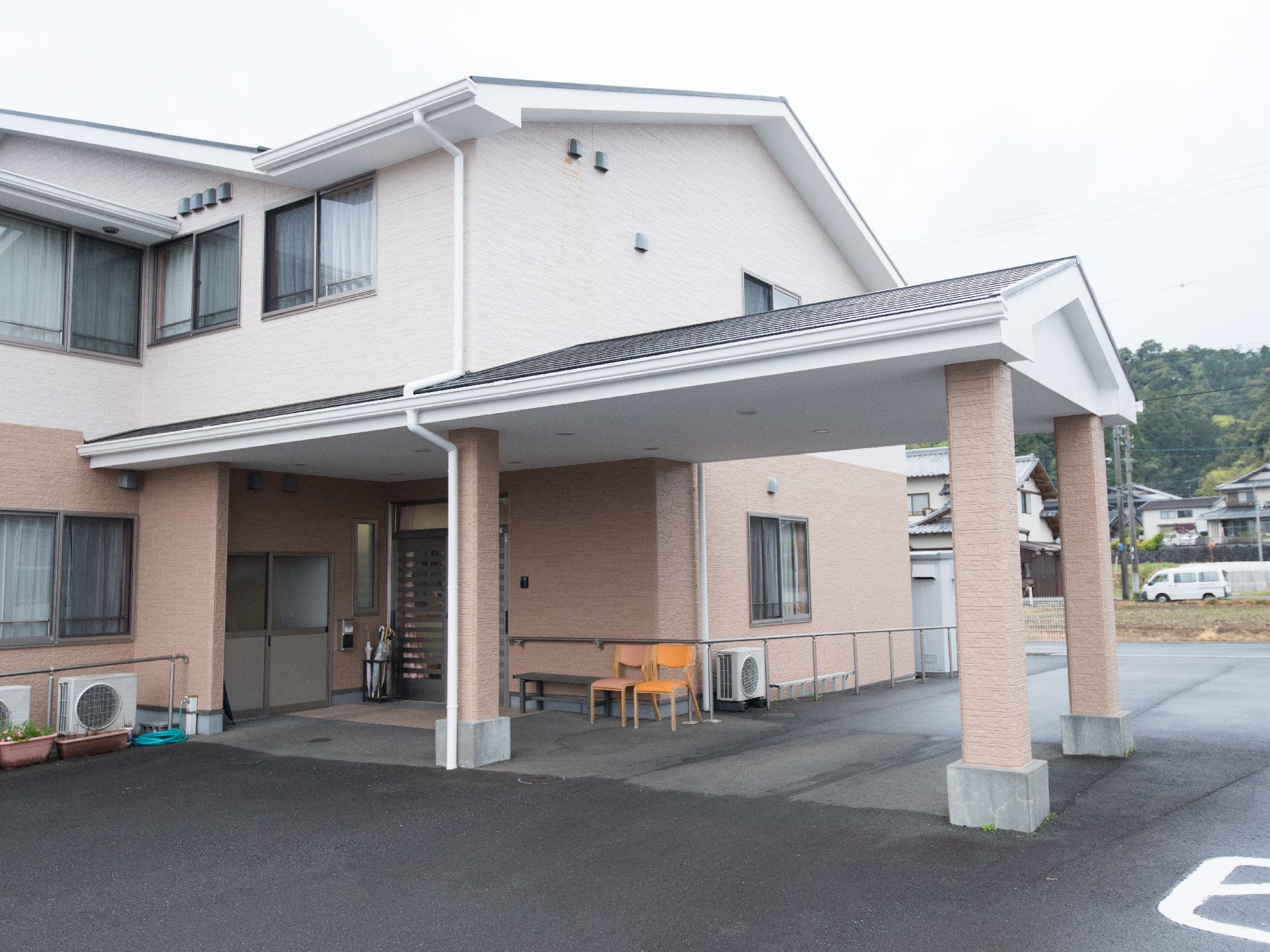 屋根付きの広い車寄せにベンチや椅子が置かれている建物