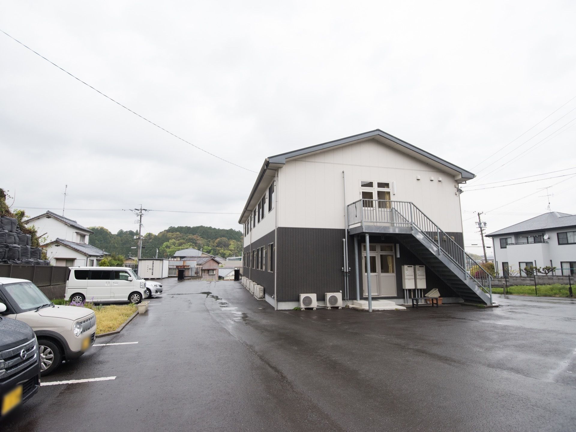 施設は、ダークグレー色とベージュ色２色の外壁になっている建物である。広い敷地が確保されており、駐車場が完備されている。