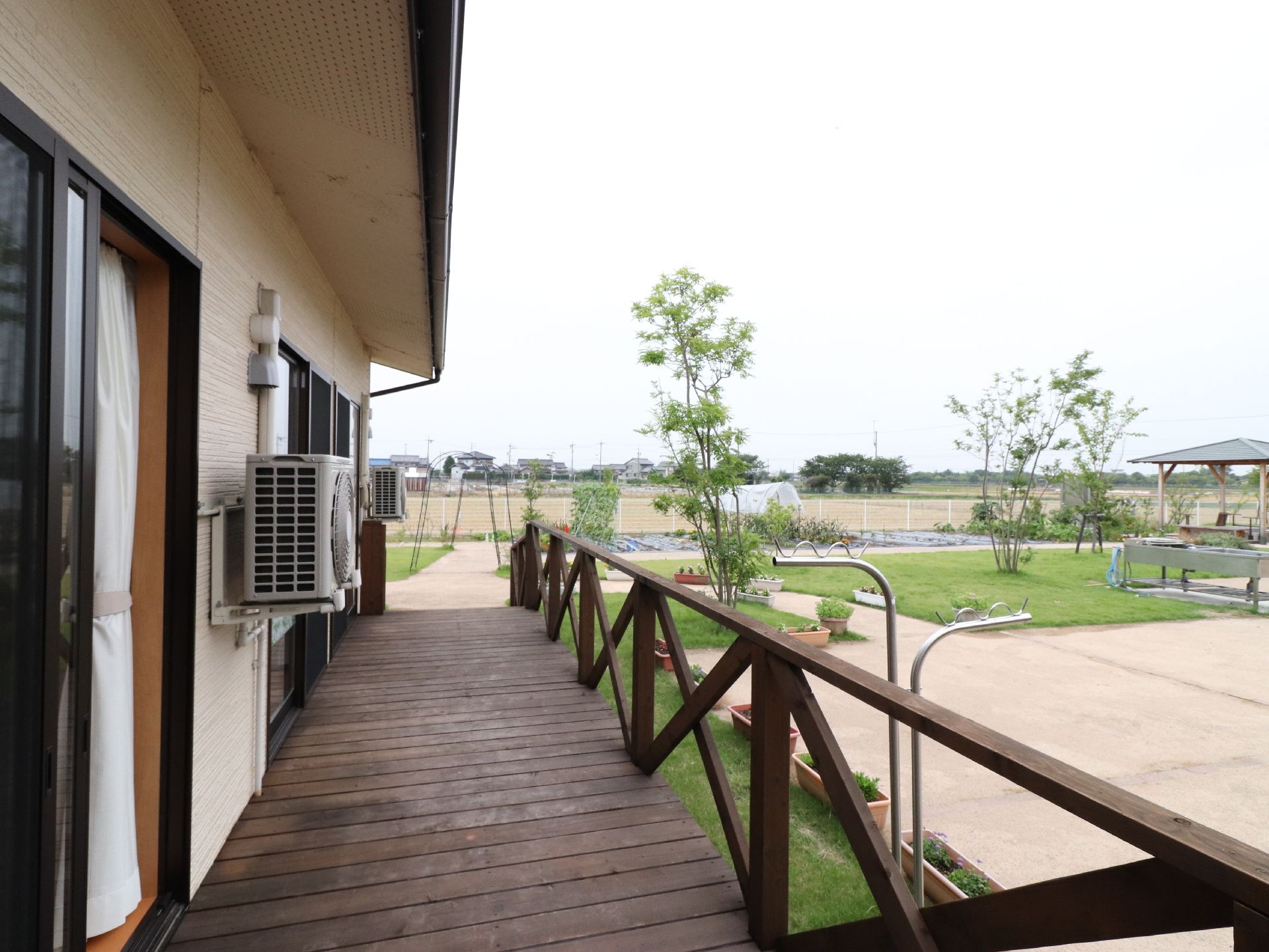 木製のテラスを抜けると園庭がある。庭には花壇がありそこには花や植物が植えられている。テラスからは部屋に続く扉がある。