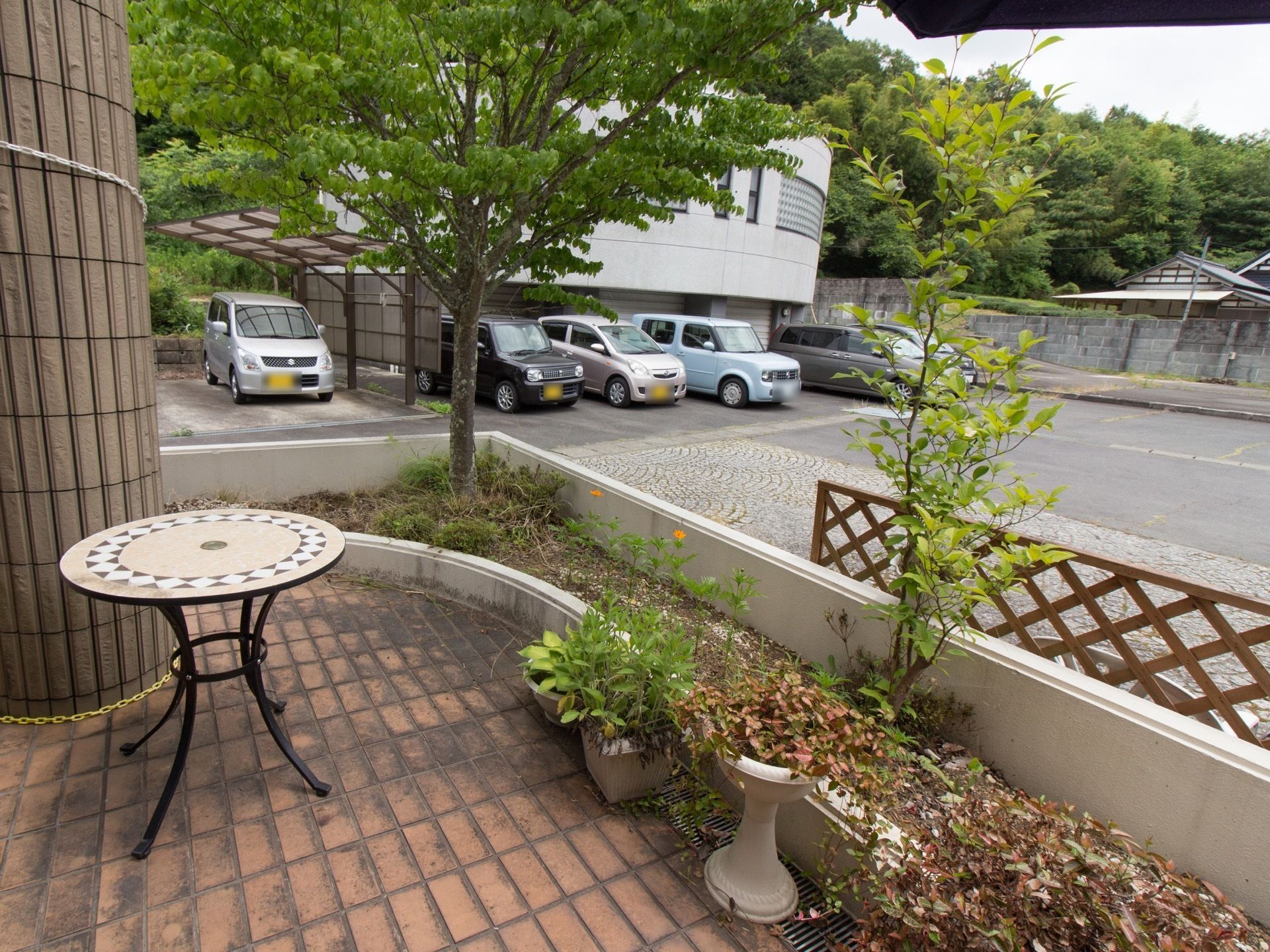 レンガ敷きのテラスがある。花壇に囲まれており、テーブルが置かれている。大きな柵などはなく見晴らしが良い。
