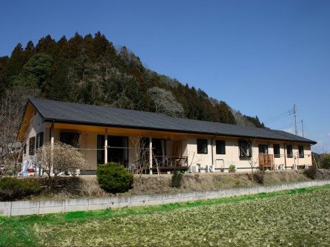 緑豊かな環境に建っている、三角屋根で横に長い平屋の建物