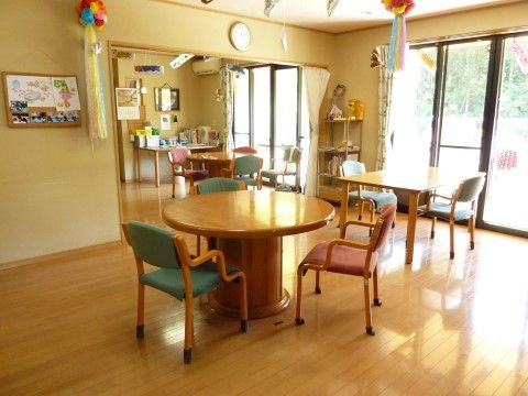 木製の丸テーブル２卓と、四角テーブル１卓が広い間隔で置かれ、椅子が２〜３脚ずつセットされている。大きな窓がある、明るく開放的な空間。