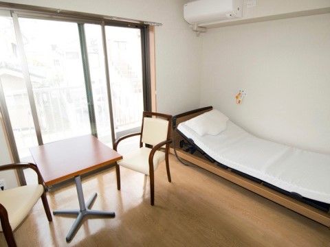 大きな窓から陽射しが差し込む、ベッドやテーブルセットなど置かれている居住スペース