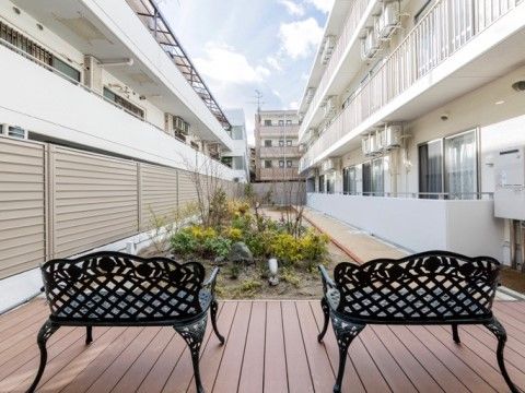 青銅色のアイアンベンチが2つ並んだ、植栽のある中庭