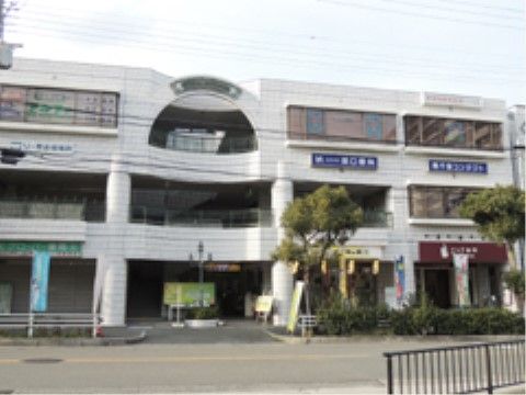 ３階建ての広い道路に面した大きな建物で、中にクリニックが入っている。目の前の歩道には、白い柵が取り付けられている。