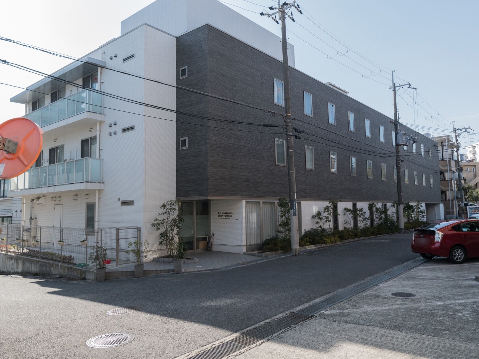白とダークブラウンの外壁になった3階建ての建物である。道路沿いにあり、玄関まで段差がないので車椅子をご利用の方も安全に移動することができる。