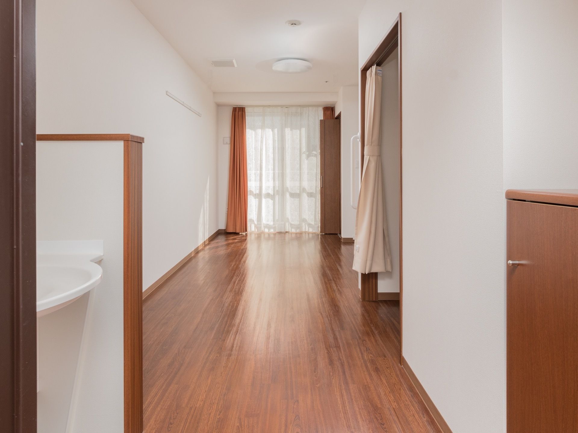 床はフローリングで、洗面所、下駄箱、クローゼットある。トイレはカーテンで仕切られている。大きな窓がある。