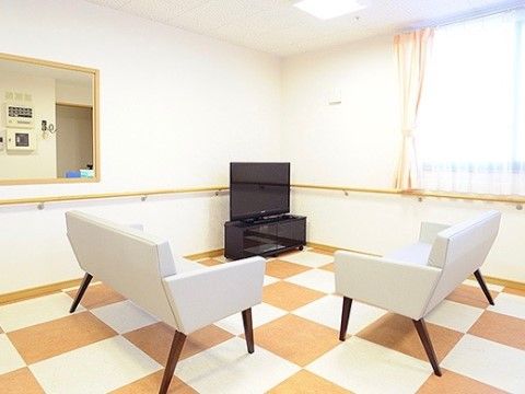 市松模様のタイルが敷かれた、テレビとソファのある共有スペース