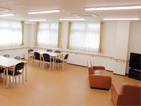 たくさんの窓と、天井に並んだ照明でとても明るい室内である。テレビが設置され、囲うようにソファが配置されている。