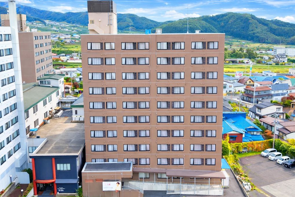 施設はマンションのような造りで10階建てで、敷地内には駐車スペースがある。窓にはカーテンがかけられている。