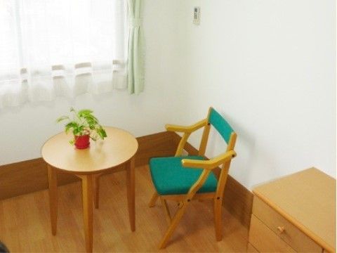 窓際に置かれた、観葉植物の飾られた一人掛けのテーブルセット