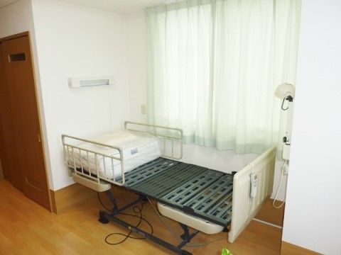 リクライニング機能が付いたシングルベッドが１台置いてある。枕元と足元には照明が設置されている。ナースコールが設けられている。