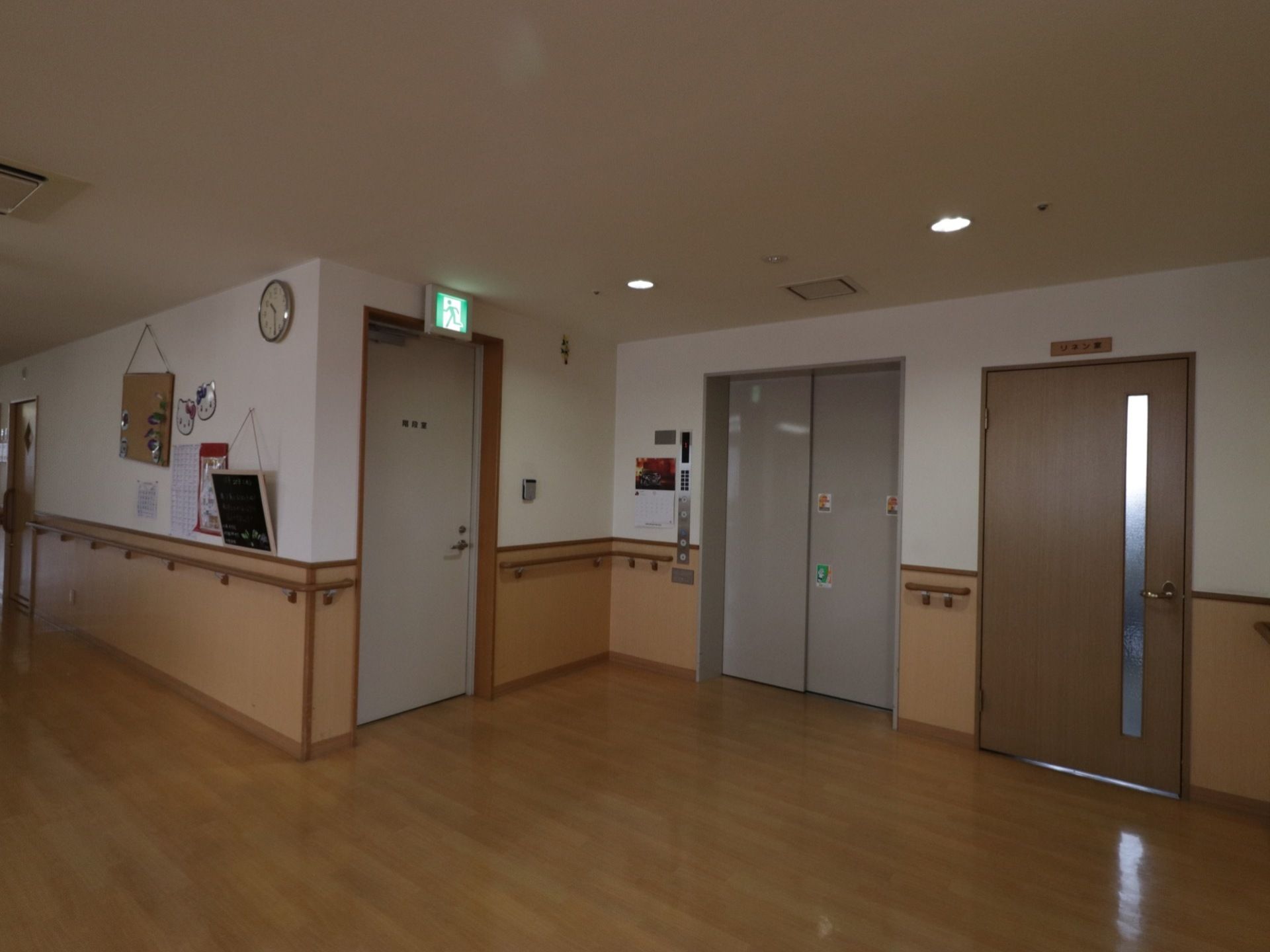 リネン室の左横に設置されたエレベーターは、グレー系の落ち着いた色でデザインされている。周辺の壁には手すりが付いている。