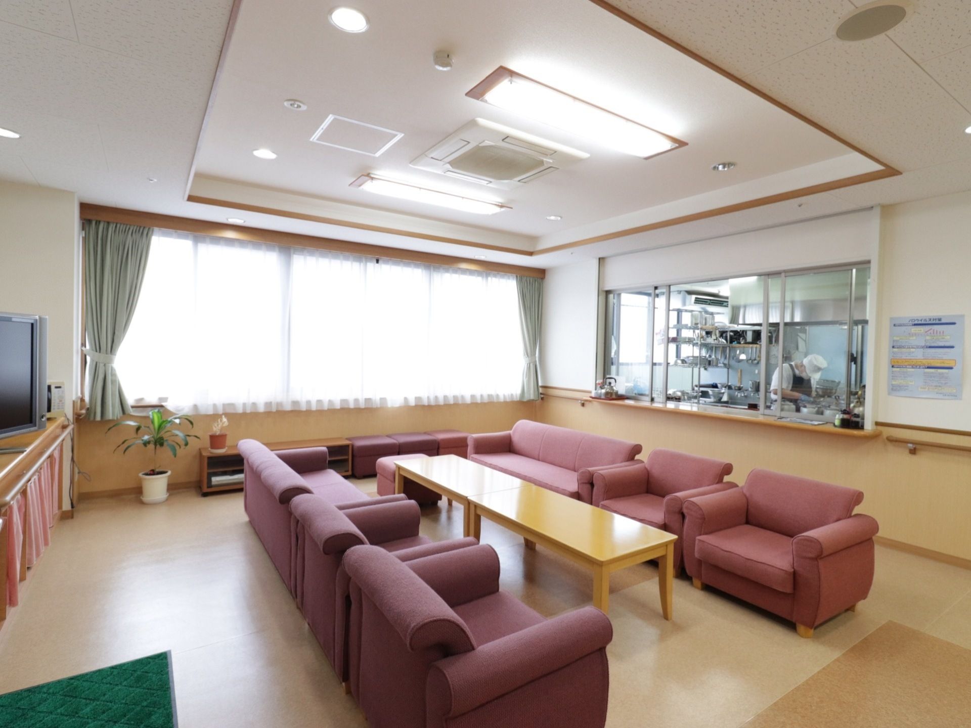 横幅のある大きな腰高窓には、白いレースと薄緑色の２種類のカーテンが掛けてある。右横の部屋は、調理場になっている。