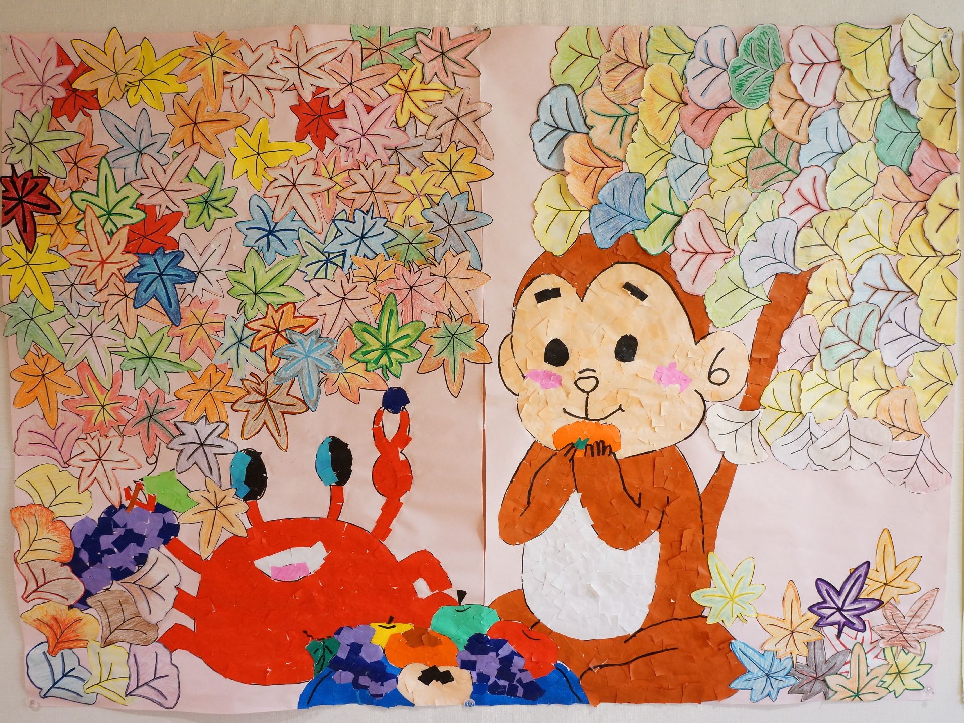 細かくちぎった色紙を張り合わせて作られた貼り絵には、銀杏や紅葉、秋の果物を楽しそうに食べる猿と蟹が描かれている。