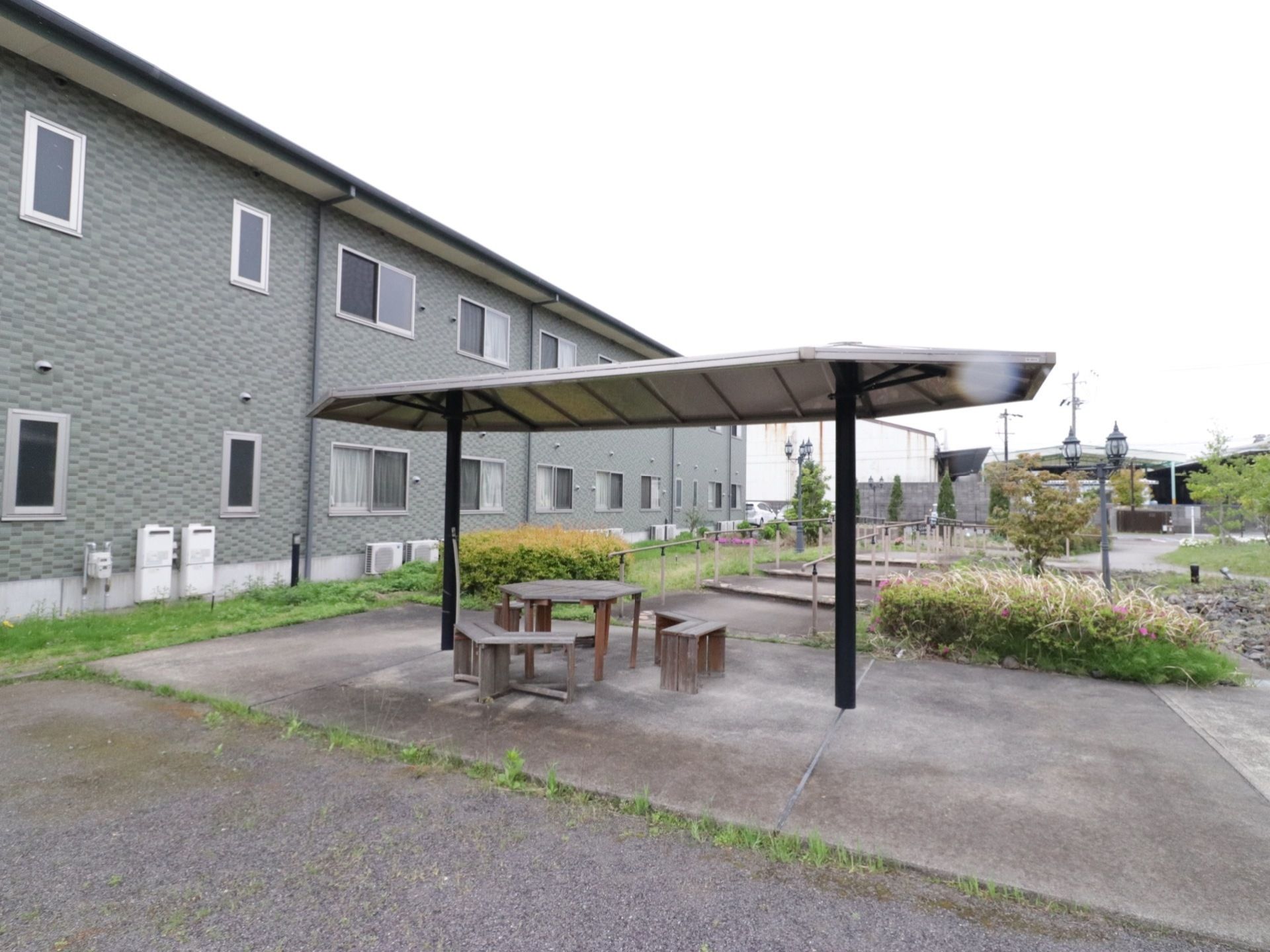 正面に、屋根付きのスペースがある。板に木製の机と椅子が置かれている。その場所から、両側に手すりの付いた通路が向こう側に伸びている。