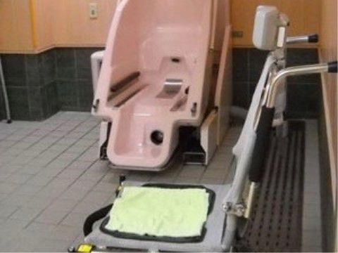 座ったままの姿勢で入浴できる浴槽が置かれている。木のぬくもりが感じられる壁には、ナースコールが設置されている。