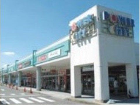 白を基調とした１階建ての広い面積を有した商業施設である。上部外壁には看板が設置されており、建物前には横断歩道がある。