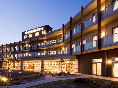 夜間もライトアップされ、エントランスから明るい光のこぼれる夜間の施設外観